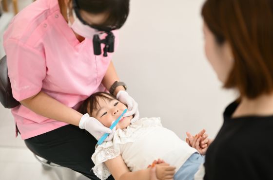 母親に手を握ってもらいながら、診療している子どもの様子